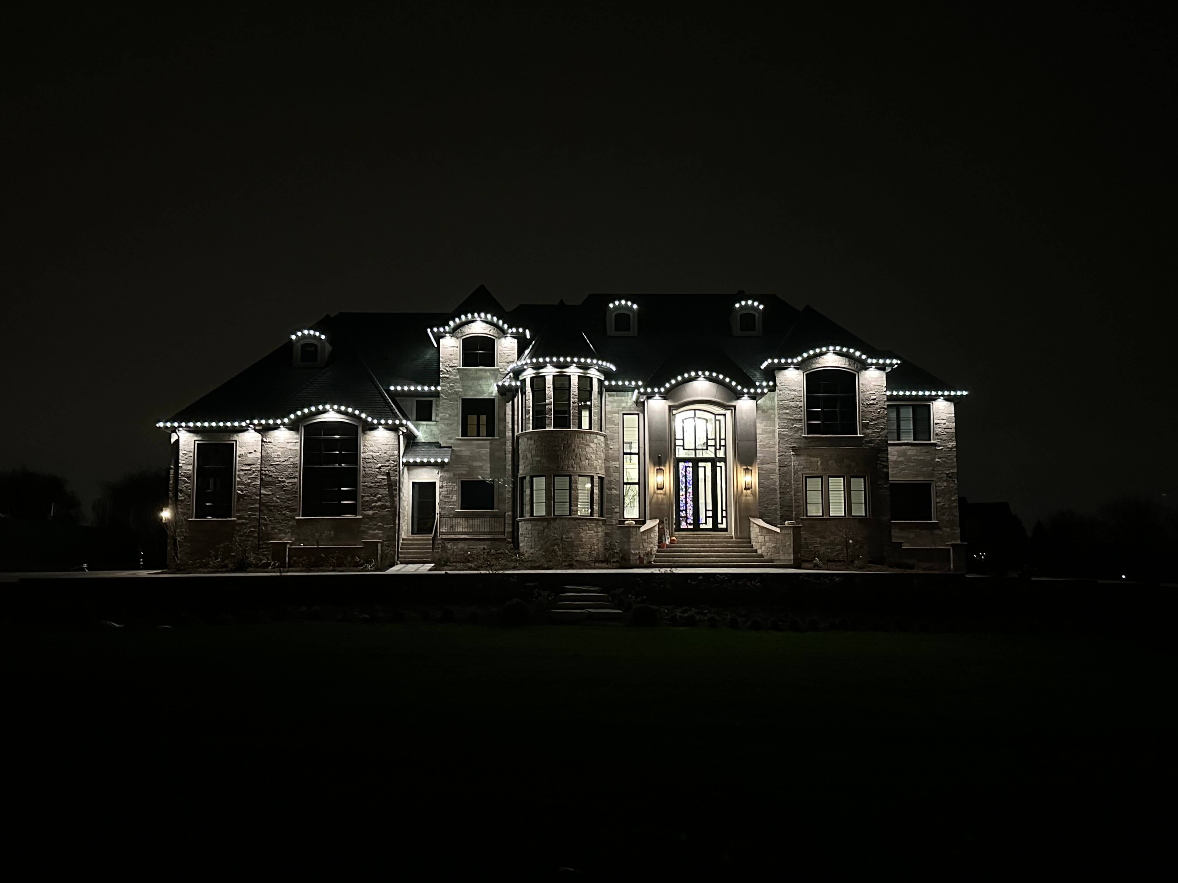 Estate home with elegant holiday lighting